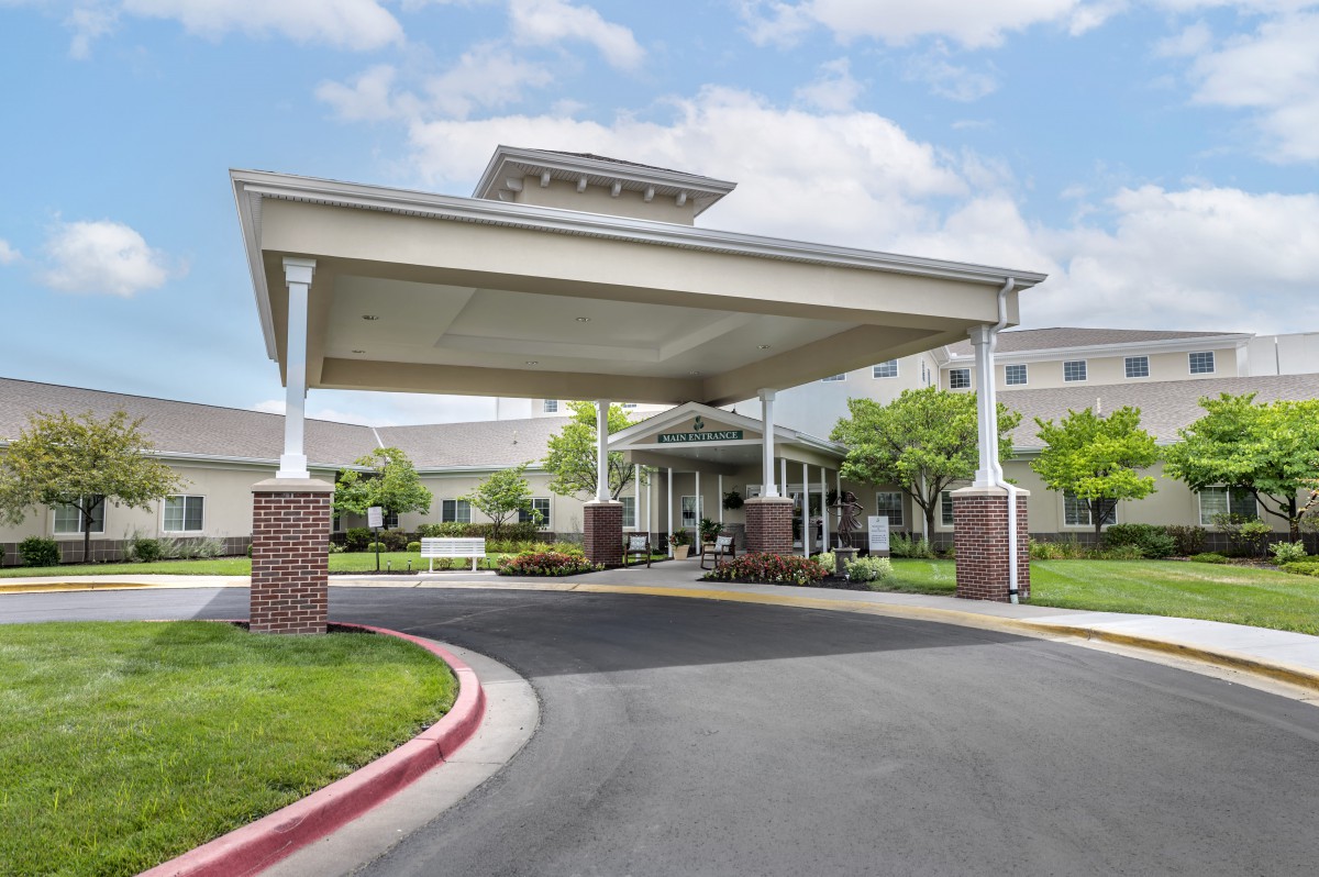 A large building entrance featuring a covered driveway and well-maintained landscaping.