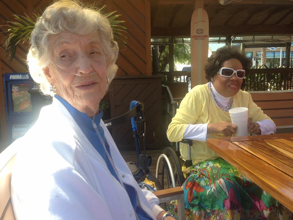 Two elderly women sitting outdoors in a cafe, enjoying a sunny day.
