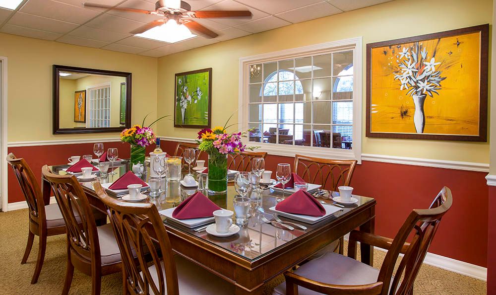 A well-decorated dining room with a neatly set table, featuring floral centerpieces and elegant place settings.