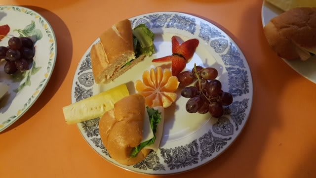 A plate with a sandwich, grapes, strawberries, and orange slices.