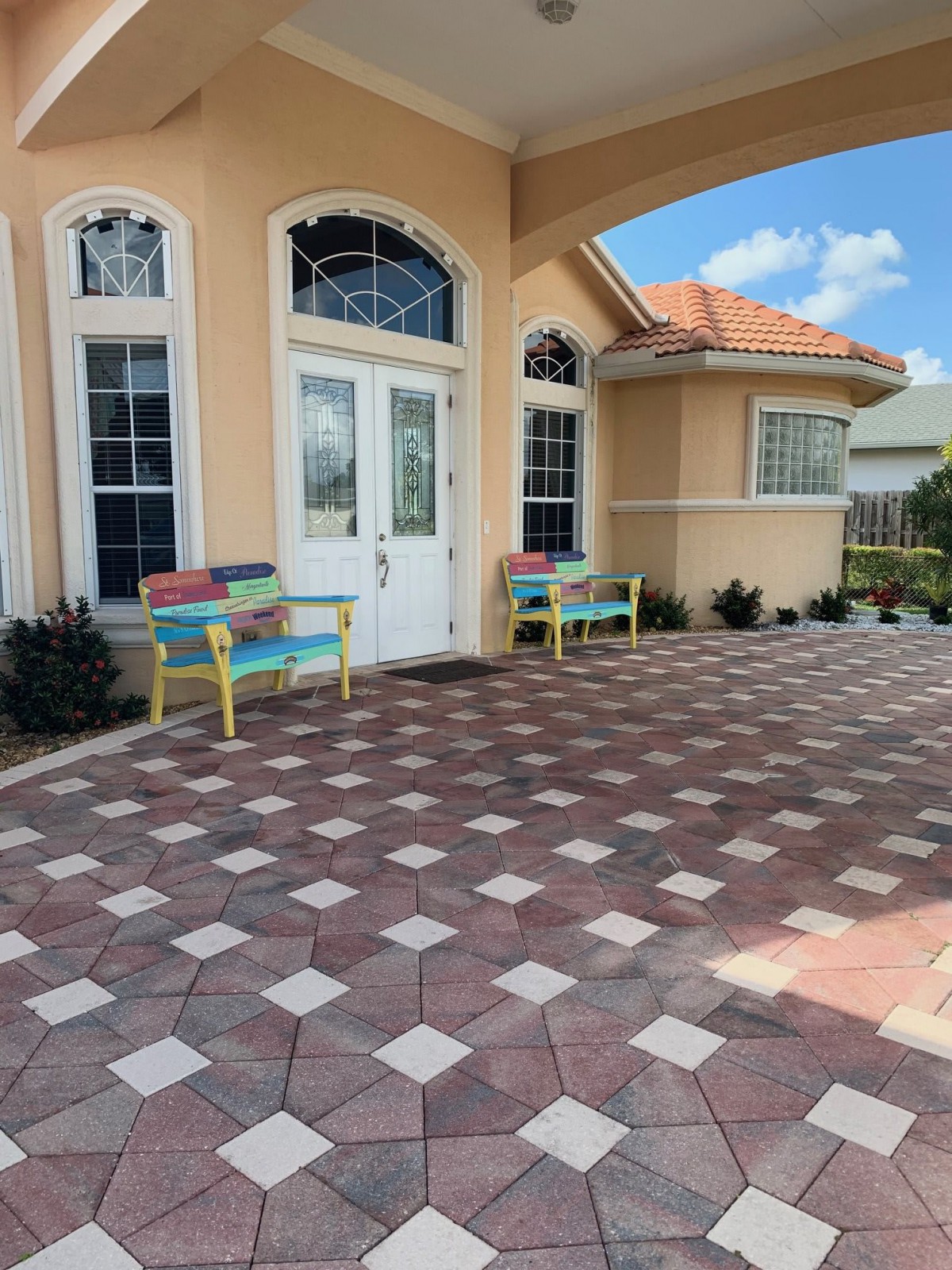 A house entrance with tile flooring and colorful benches on the patio.