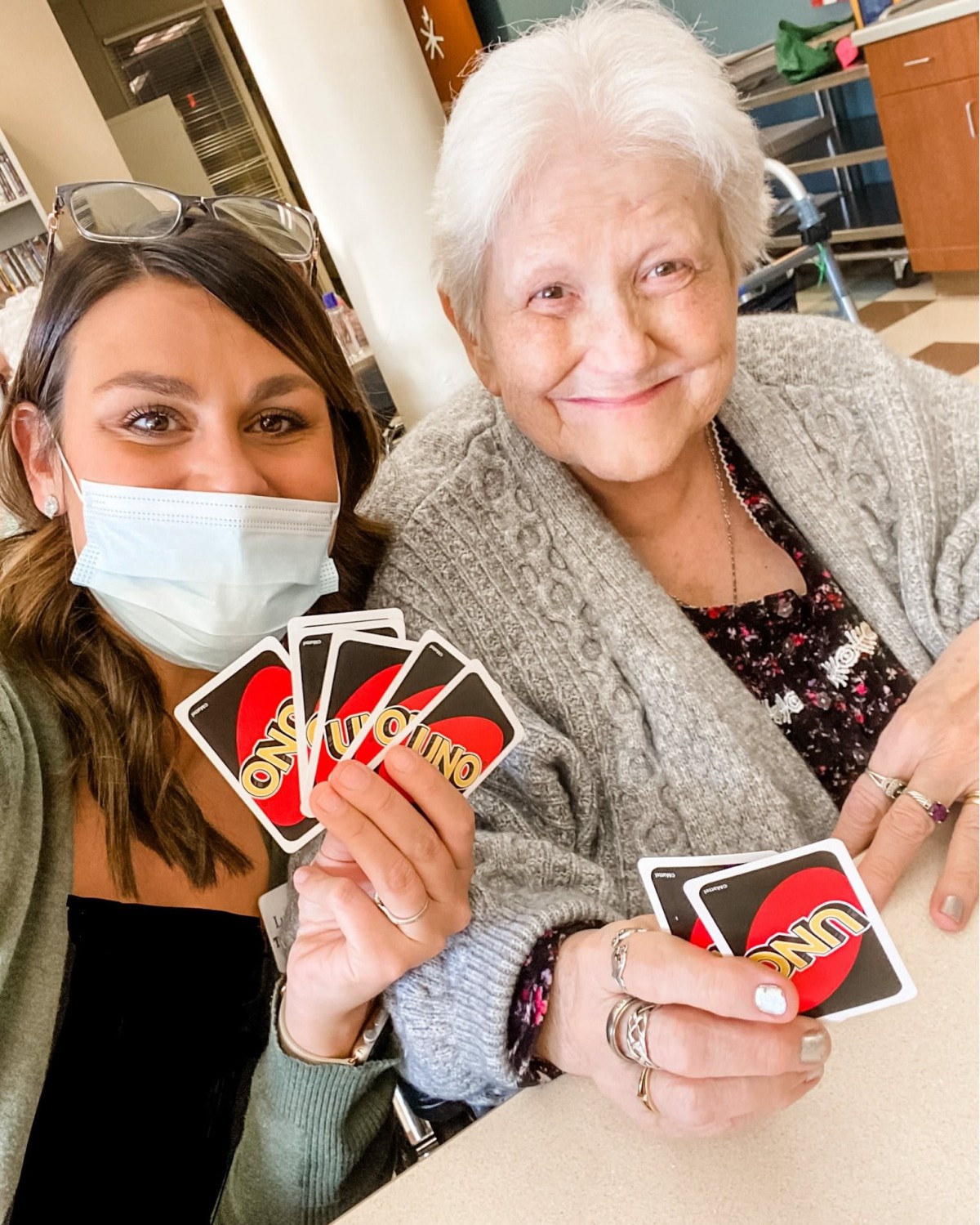 Two people enjoying a game of UNO together, with one person wearing a mask.