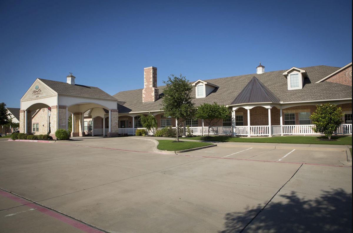 A large residential building with a spacious driveway and clear blue sky.