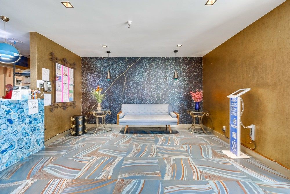 A modern living room featuring a stylish sofa, artistic wall decor, patterned carpet, and decorative flower vases.