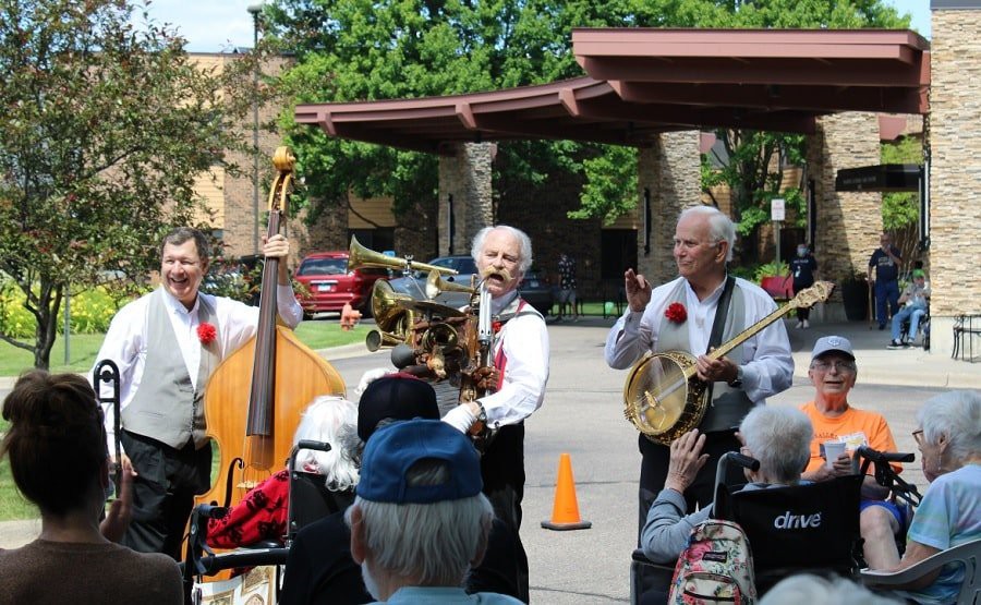 A group of musicians performing outdoors for an audience on a sunny day.
