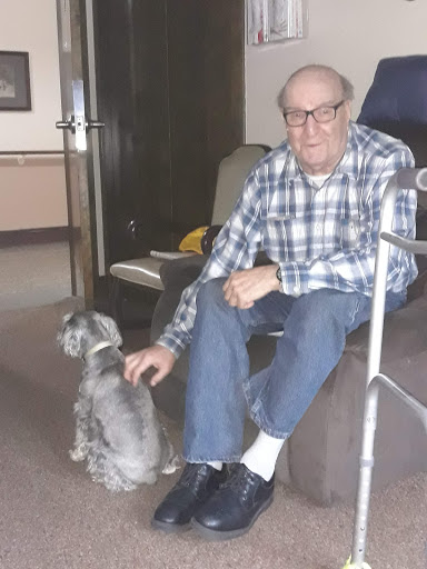 An elderly man enjoying the company of his dog in a cozy indoor setting.
