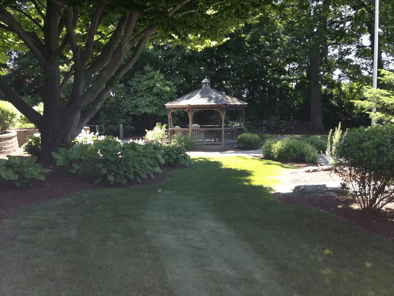 A serene garden with a gazebo surrounded by lush trees and greenery.