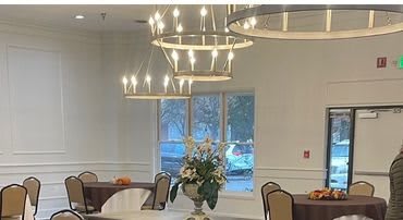 A beautifully arranged dining area with elegant chandeliers and a floral centerpiece.