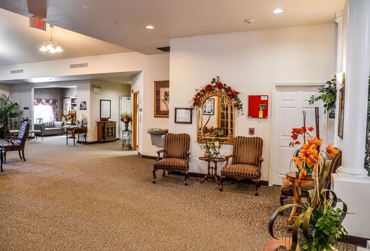A cozy lobby area with chairs, a decorative mirror, and warm lighting.