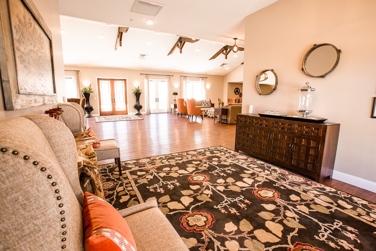 A spacious living room with elegant interior design, featuring a large patterned rug, wooden flooring, and stylish furniture and decor.