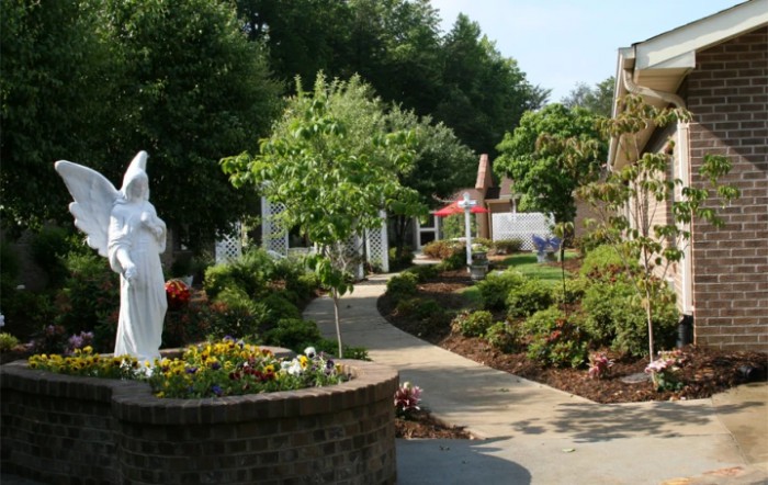 A serene garden pathway with lush greenery and a statue.
