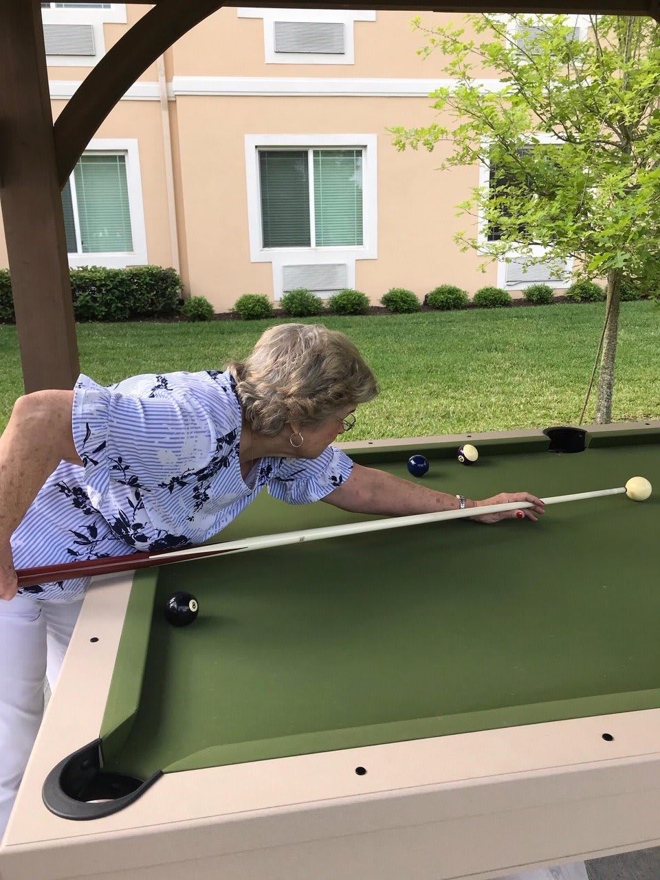 A person is playing billiards on an outdoor pool table.