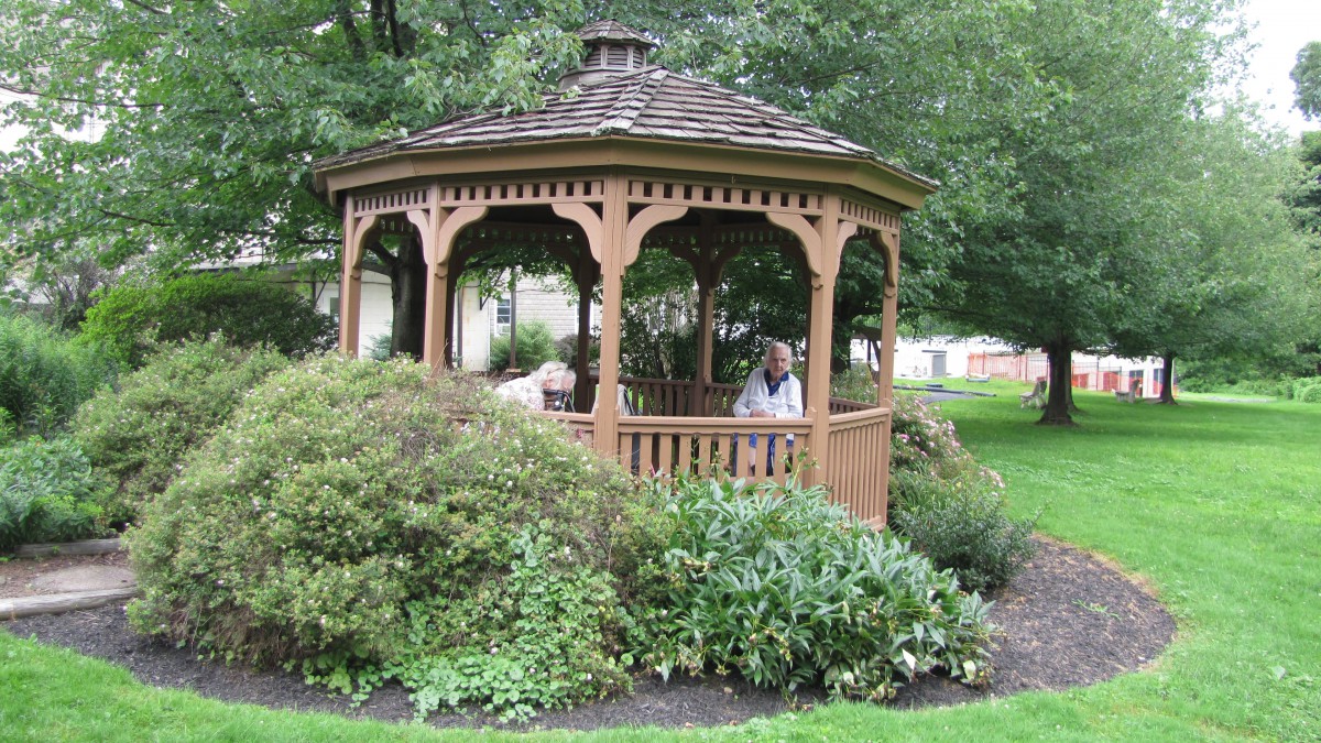 A wooden gazebo nestled in a lush garden setting.