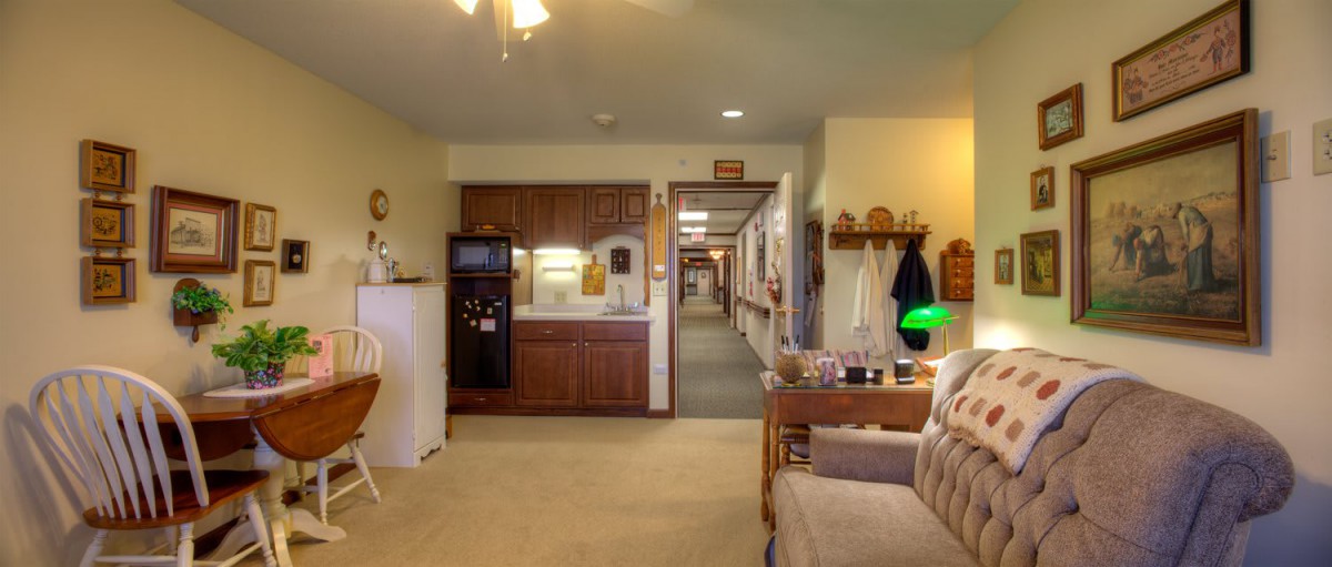 A cozy living space with a view into a long hallway, featuring warm lighting and comfortable furnishings.