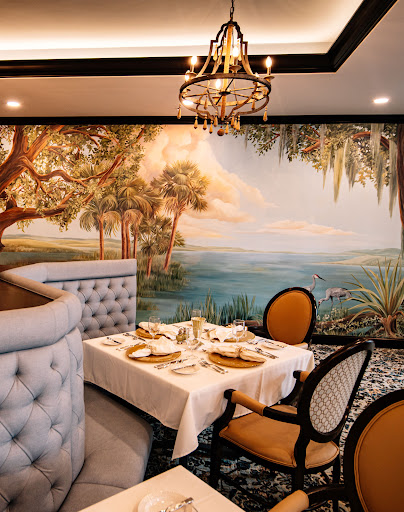 A beautifully designed restaurant interior featuring a scenic wall mural, elegant furnishings, and a cozy dining atmosphere.