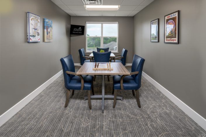 A small conference room with a table and four chairs, featuring wall art and a window.