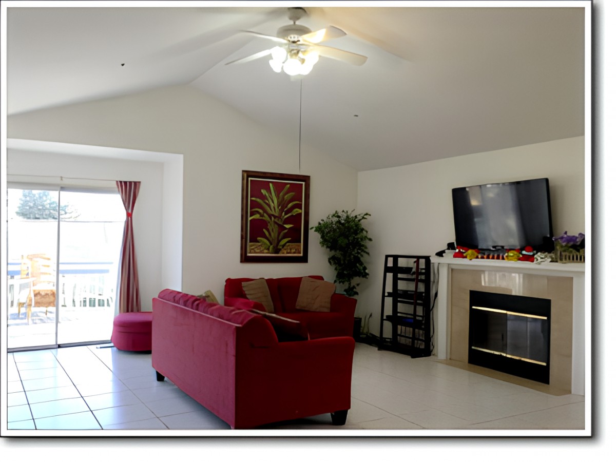 A cozy living room with a red sofa, television above a fireplace, and tasteful decor including a potted plant.