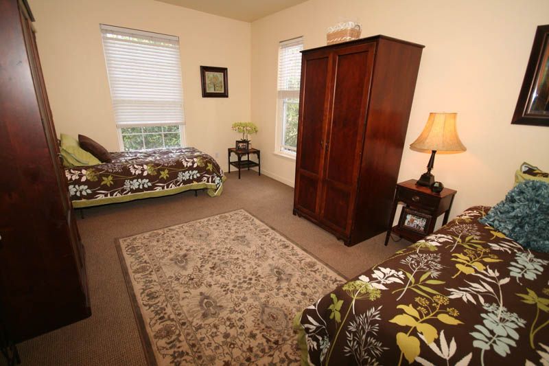 A cozy bedroom with two single beds, a wooden wardrobe, and a patterned carpet.