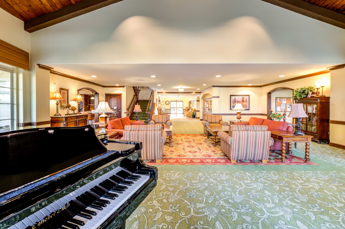 A spacious living room with a grand piano, featuring elegant furniture and tasteful decor.