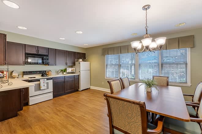 A modern kitchen and dining area featuring wooden flooring, sleek appliances, and elegant lighting.