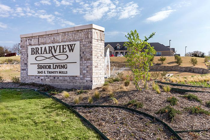 A senior living community sign with well-maintained landscaping in front of a residential building.