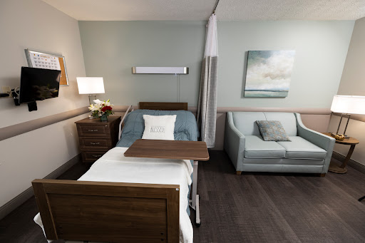A modern hospital room equipped with a patient bed, a comfortable sofa, and tasteful decor.