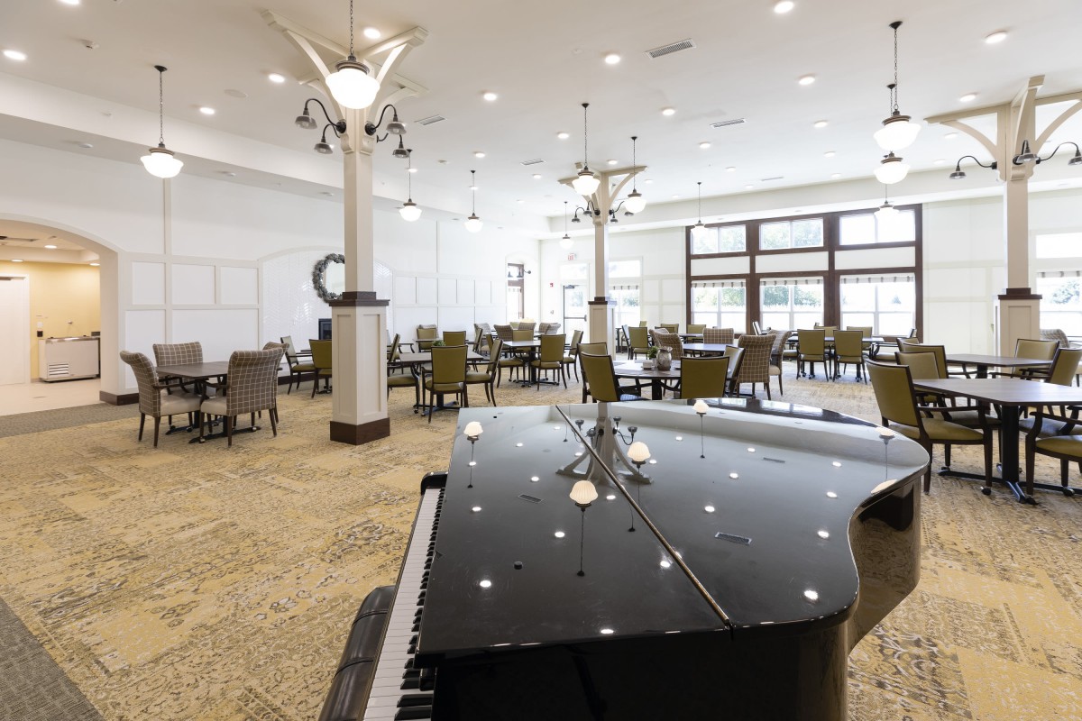 A modern dining area featuring a grand piano and contemporary lighting fixtures.