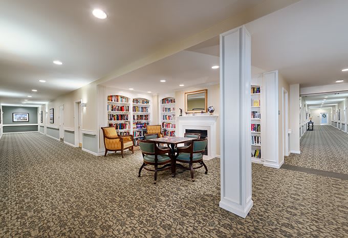 A cozy library area with bookshelves, a table, and chairs.
