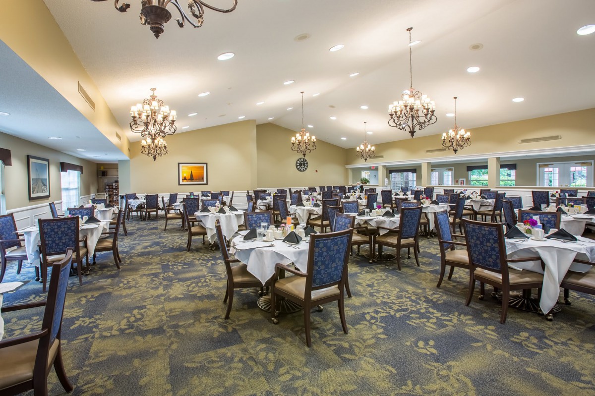 A spacious and elegantly decorated dining room with neatly arranged tables and chandeliers.