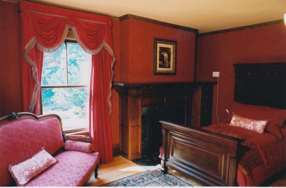 A classic living room with red walls, featuring a fireplace and elegant furnishings.