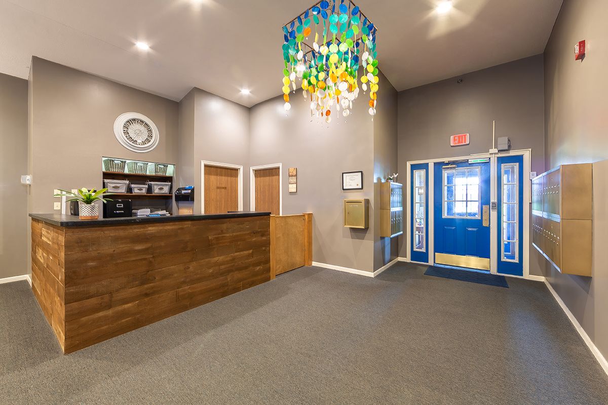 A cozy reception area with a wooden desk and a colorful chandelier.