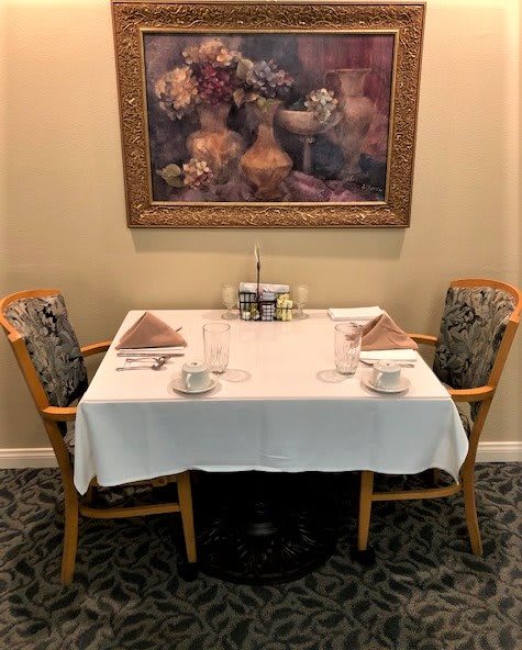 A neatly set dining table for two with a decorative painting on the wall in a restaurant.