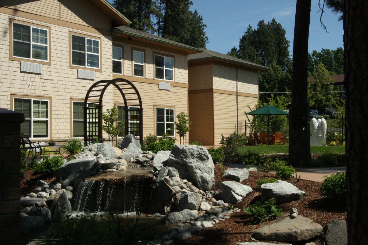 A landscaped garden with a small waterfall in front of a modern building.