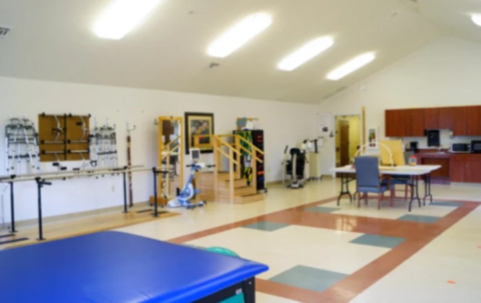 A spacious physical therapy room equipped with various exercise machines and rehabilitation tools.
