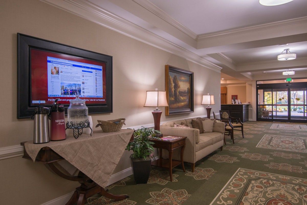 A cozy hotel lobby with a sofa, decorative lamps, and artwork on the walls.