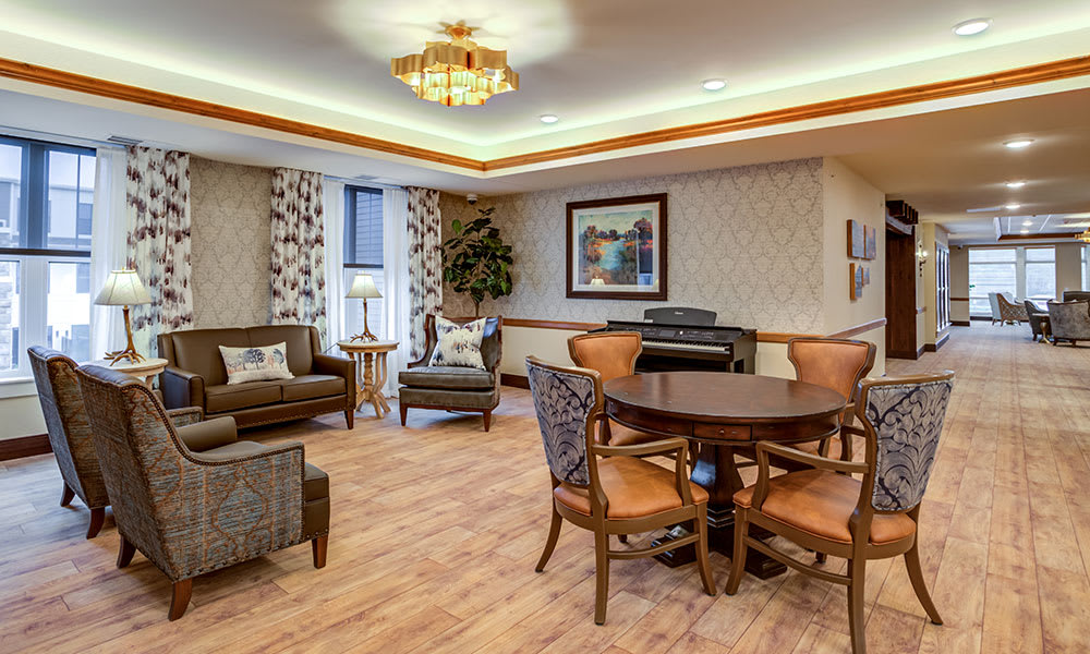 A cozy living room featuring comfortable seating, a dining table with chairs, and a piano against the wall.