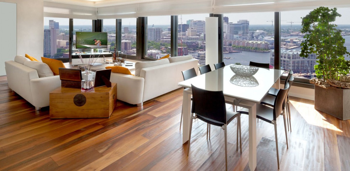 A modern apartment featuring a spacious living room and dining area with large windows overlooking the city skyline.