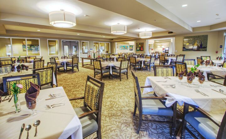 A spacious dining area with neatly arranged tables and chairs, featuring elegant lighting and decor.