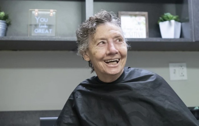 A person smiling while sitting in a hair salon.