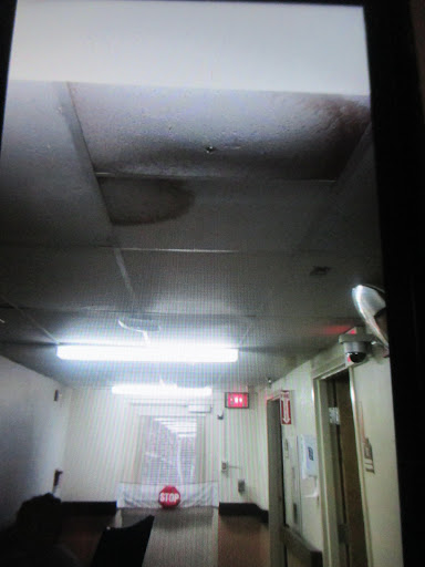 A view of a damaged ceiling in an indoor hallway, showing signs of water damage.