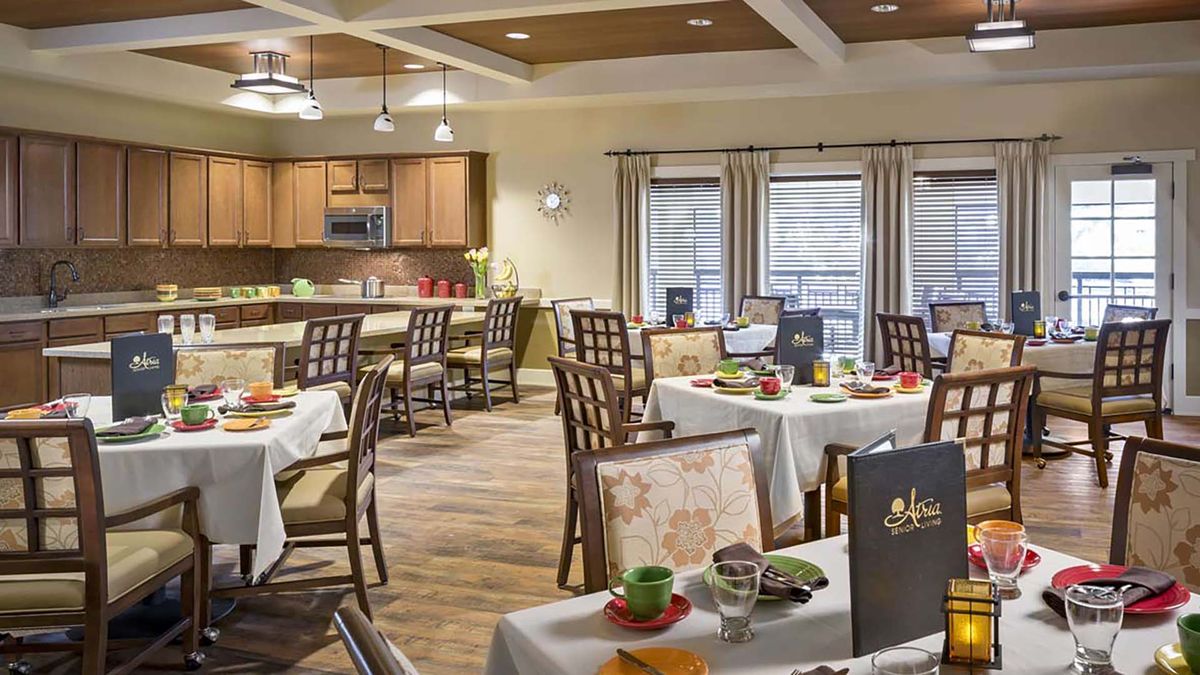 A modern dining area with elegantly set tables and a view of the open kitchen.