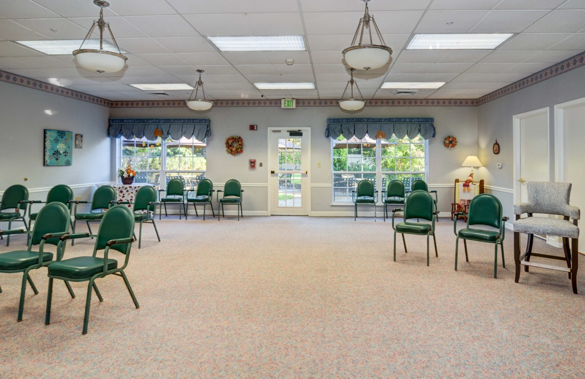 An empty meeting room with green chairs arranged in a spacious interior.