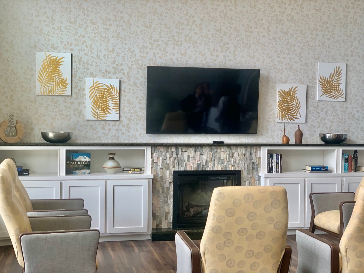 A modern living room with a mounted TV above the fireplace, surrounded by stylish artwork and comfortable seating.
