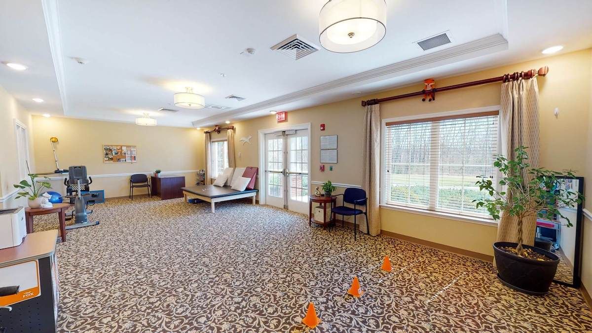 A spacious room with carpeted flooring, chairs, a table, and ample lighting.