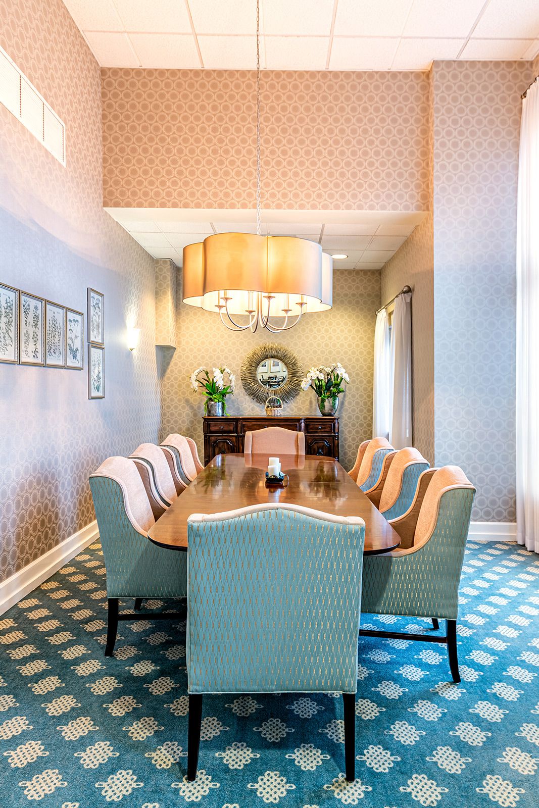 A stylish dining room with a large table, upholstered chairs, and a decorative chandelier.