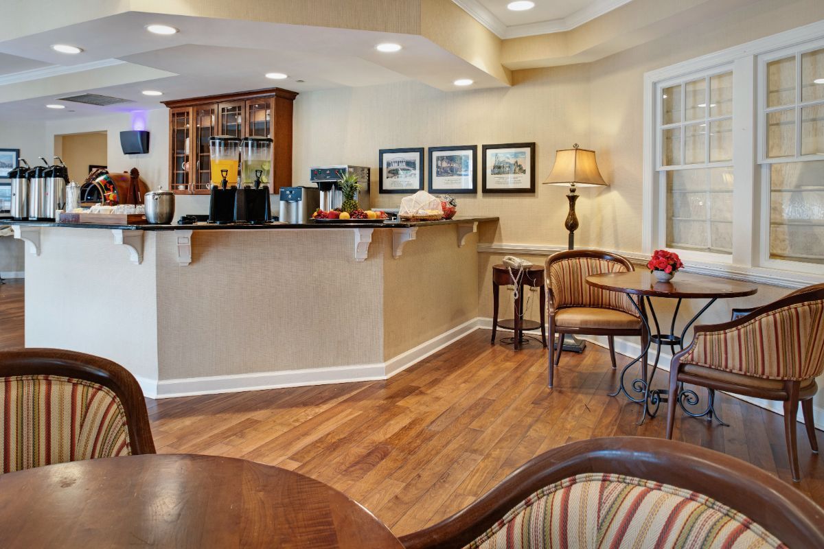 A cozy cafe interior with a bar counter and seating area, featuring wood flooring and warm lighting.