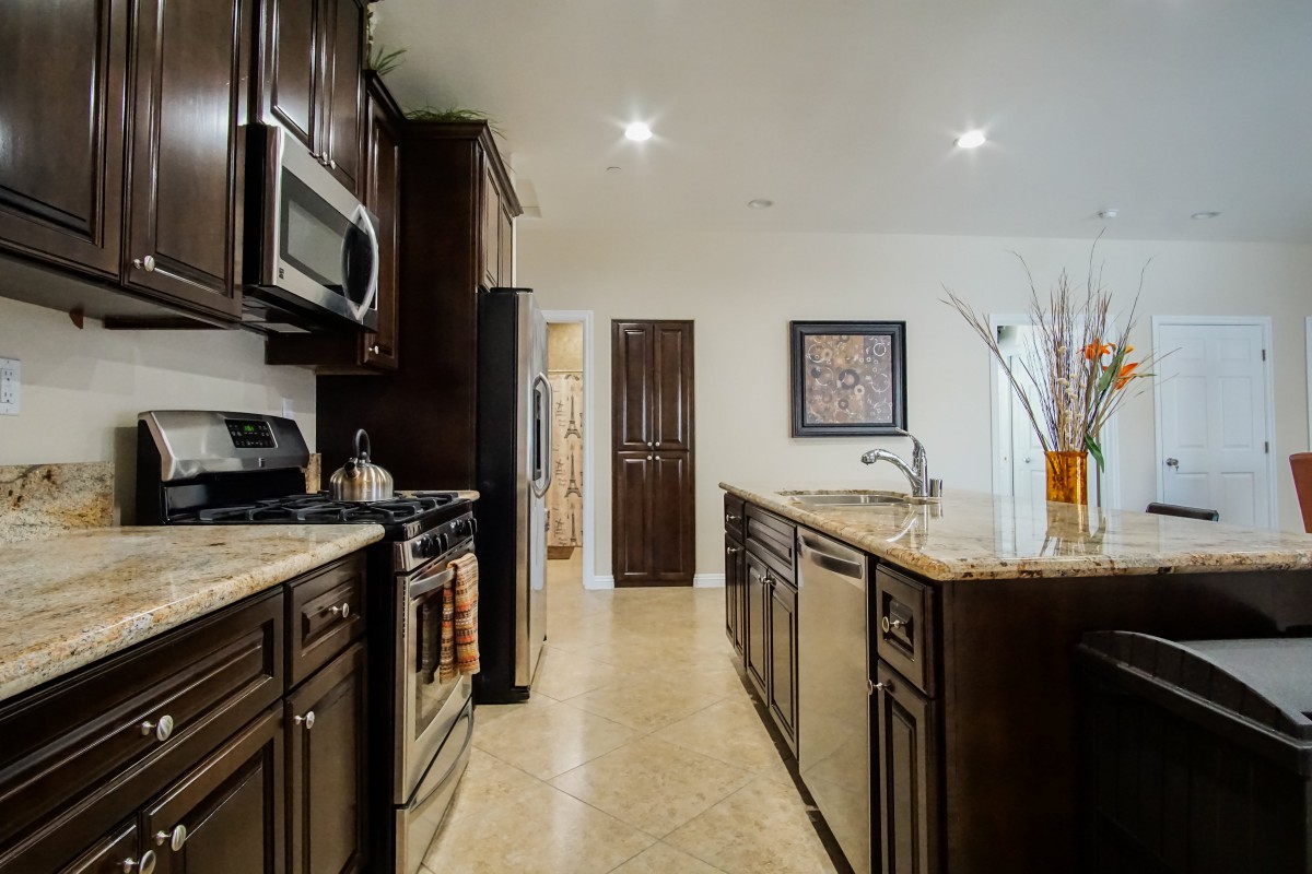 A modern kitchen with dark wood cabinets and stainless steel appliances.