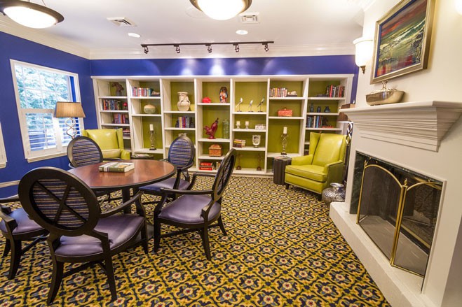 A cozy library room with bookshelves, a fireplace, and comfortable seating.