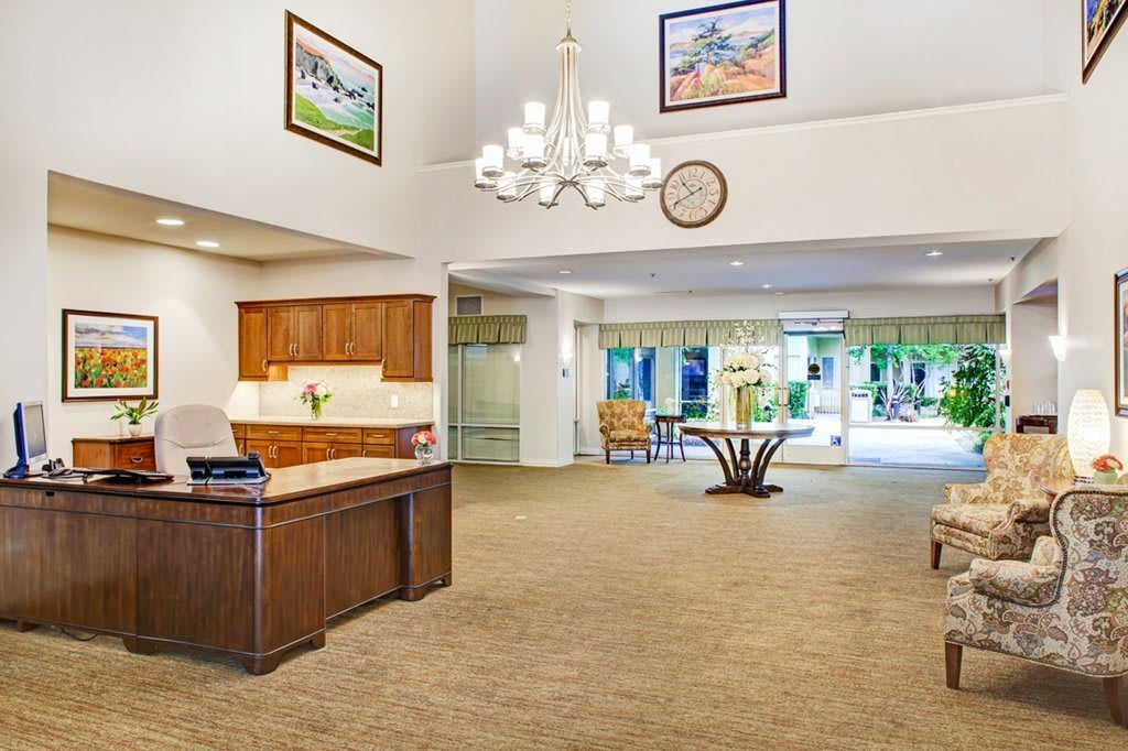 A spacious hotel lobby with a reception desk and elegant chandelier.
