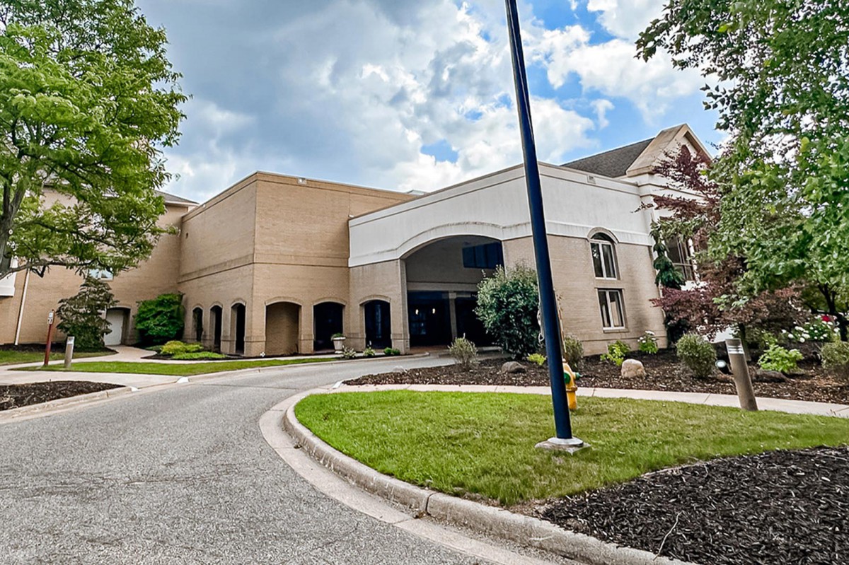 A modern building with a welcoming entrance and landscaped surroundings under a partly cloudy sky.